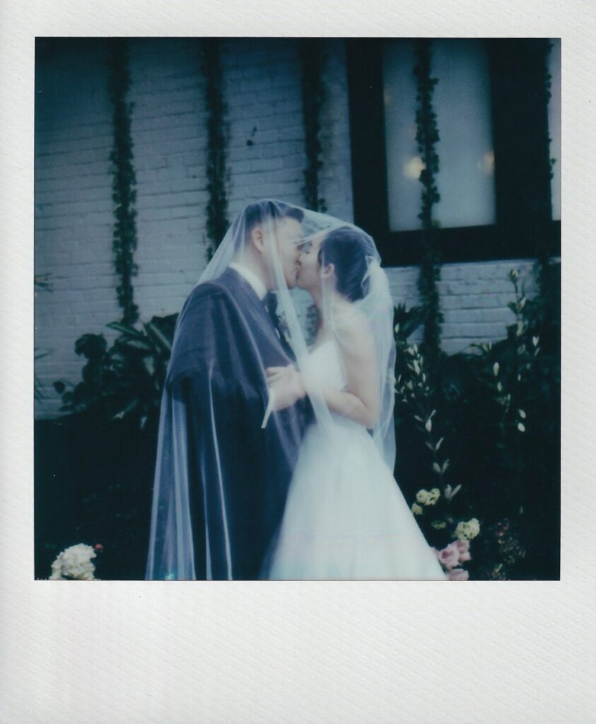 Polaroid of bride and groom kissing under the veil
