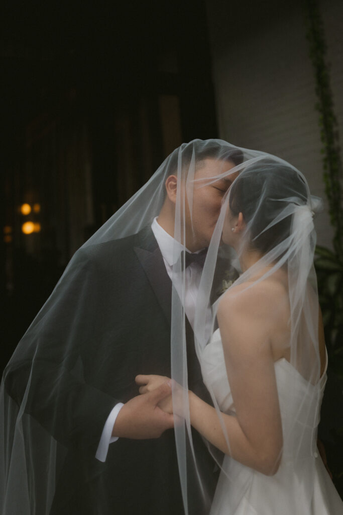 Bride and groom kissing under the veil