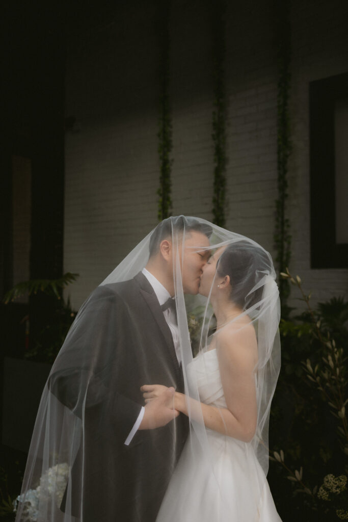 Bride and groom kissing under veil