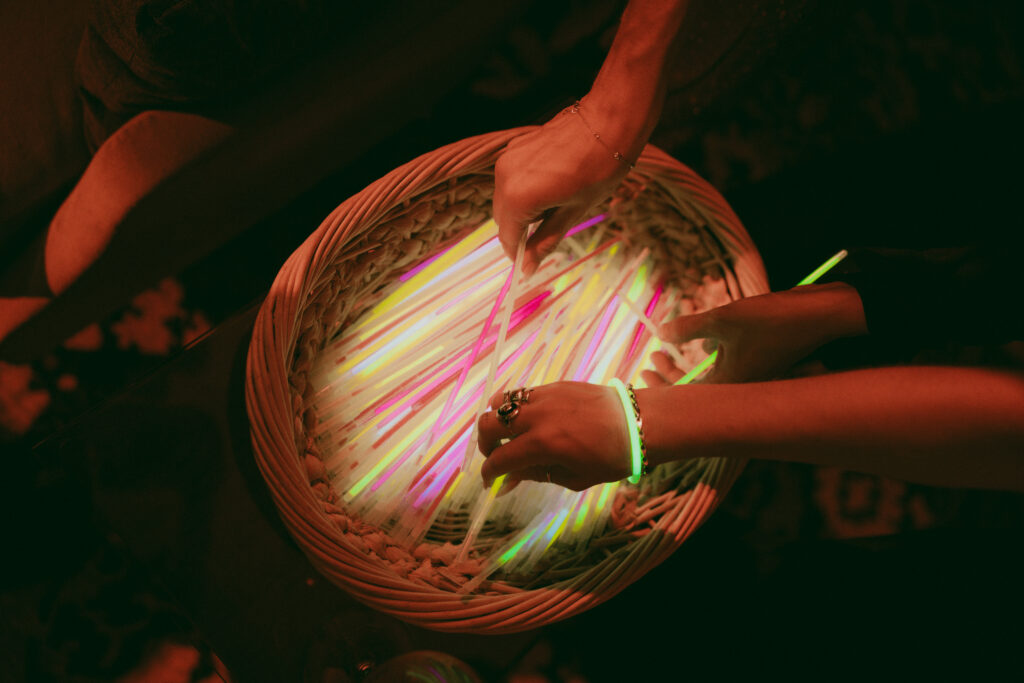Wedding guests grabbing glow sticks from a basket during the wedding reception