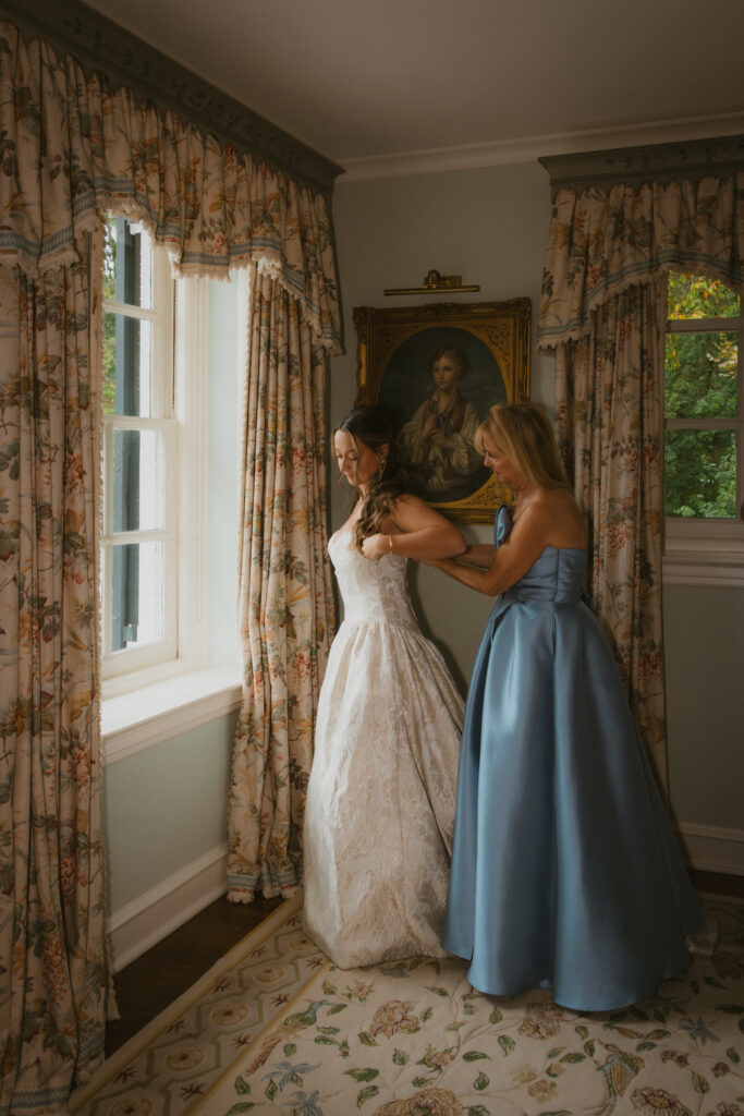 Bride putting on her wedding dress with the help of her mother 