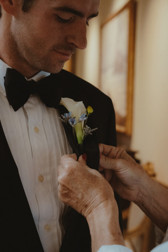 Mother of the groom putting on the groom's boutonniere 