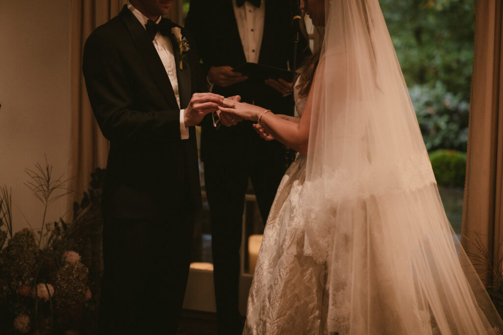 Groom putting ring on the bride's finger during ceremony