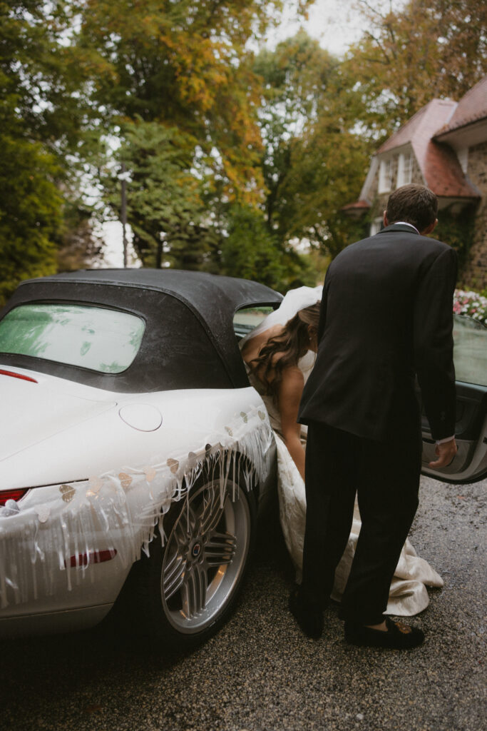 Groom opening car door of the wedding getaway car for the bride 