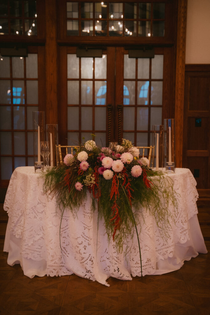 Sweetheart table with white lace tablecloth and floral centerpiece
