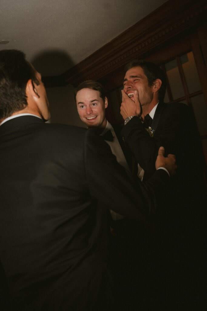 Groom laughing with groomsmen at the reception