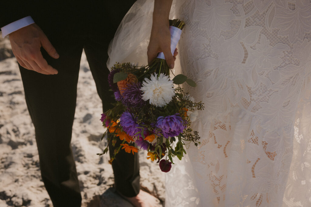 Close up of the bridal bouquet in front of the bride and groom's legs