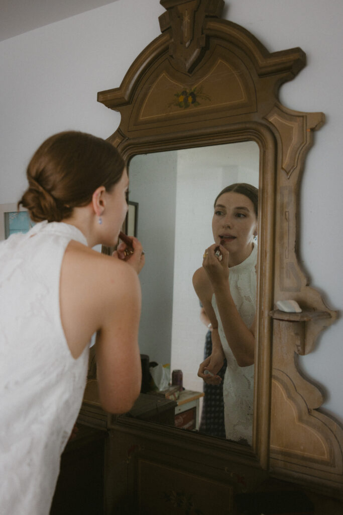 Bride putting on makeup in the mirror