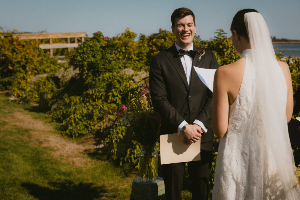 Groom laughing while bride reads her vows 