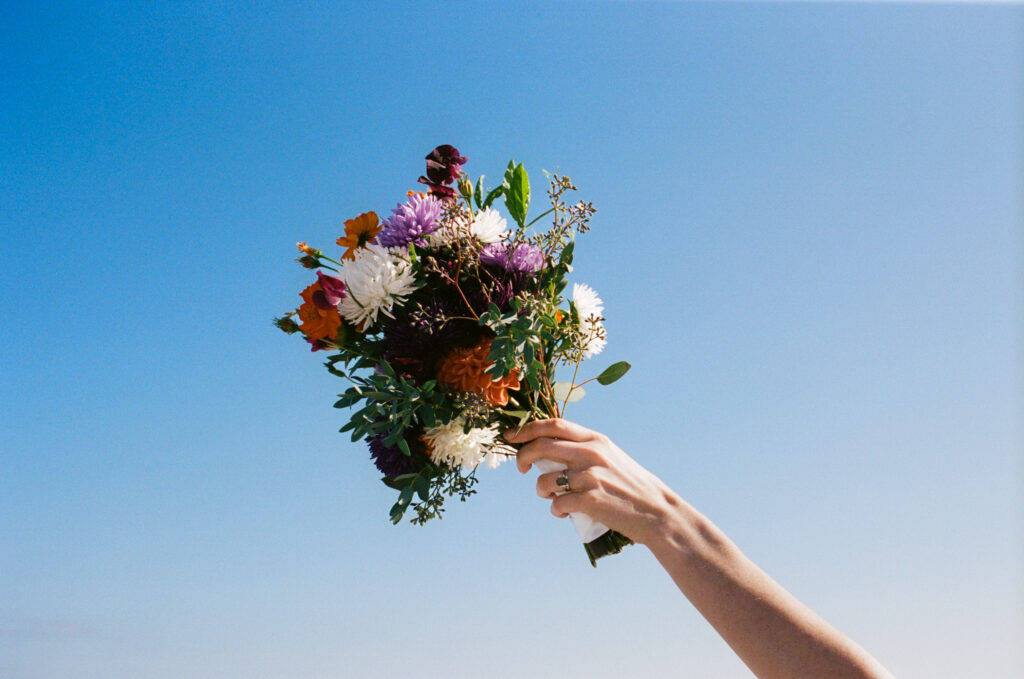 Bridal bouquet held in the air against the blue sky