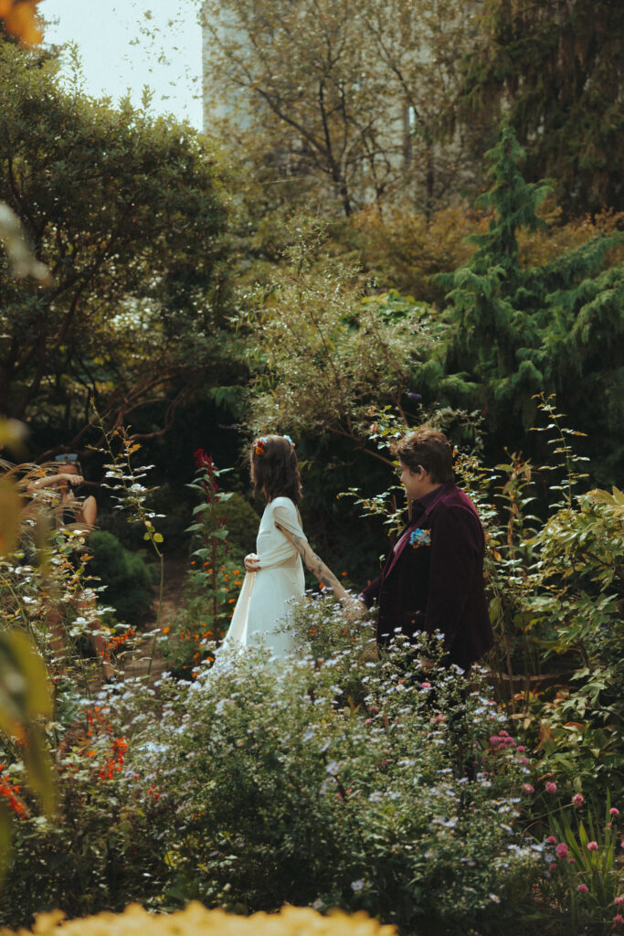 Brides walking through a garden holding hands 