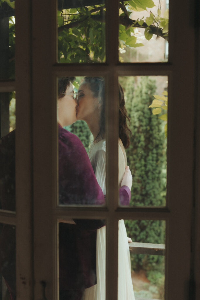 Brides kissing, taken through a closed window