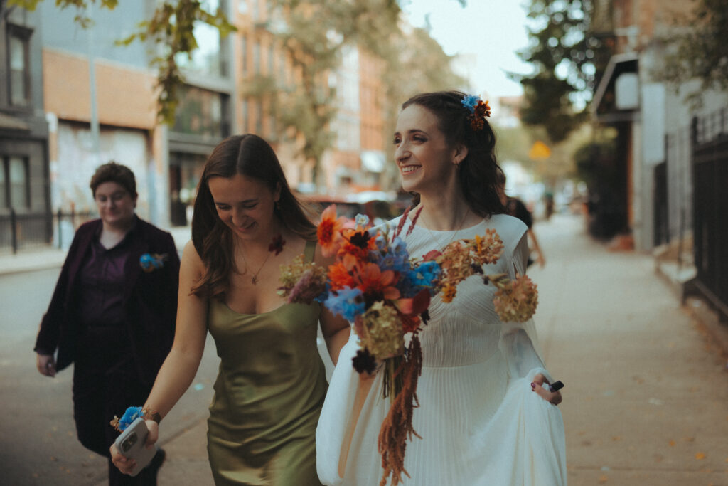 Bride smiling walking down the street in new york city with her maid of honor 