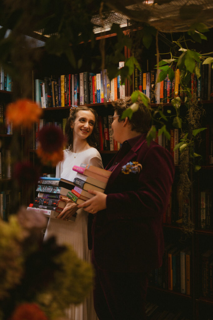 Brides holding stacks of their favorite books at their housing works bookstore wedding