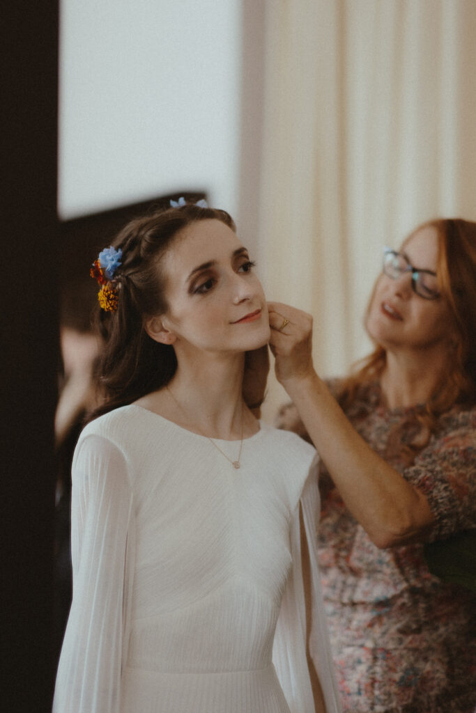 Mother of the bride helping the bride put on jewelry