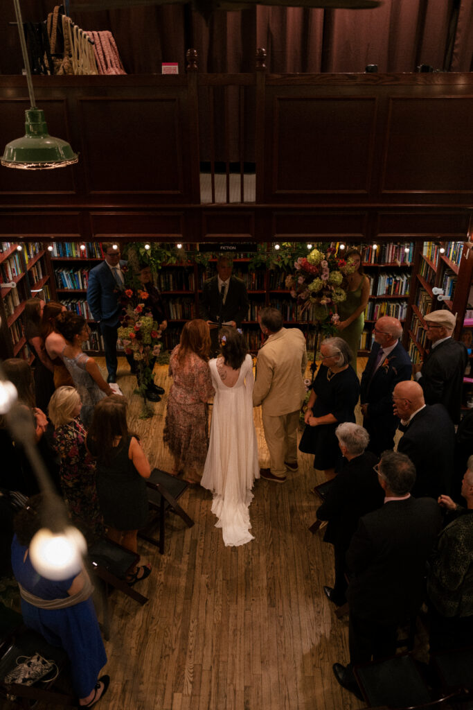 Bride walking down the aisle with her parents in a housing works bookstore wedding ceremony
