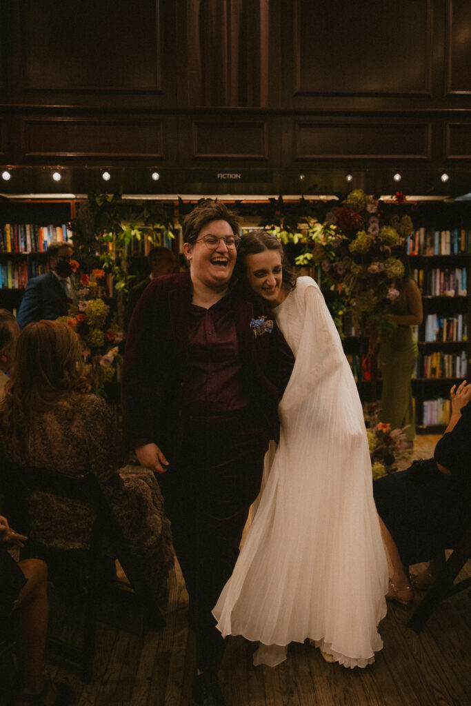 Brides laughing and walking back down the aisle as a married couple after wedding ceremony