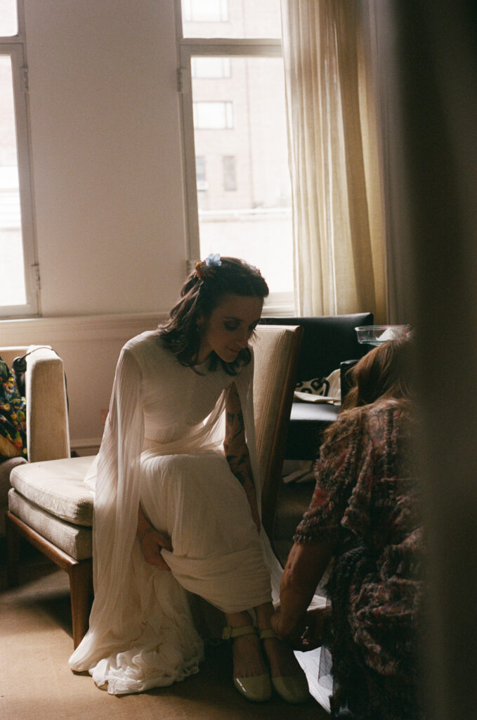 Mother of the bride helping the bride put on her shoes 