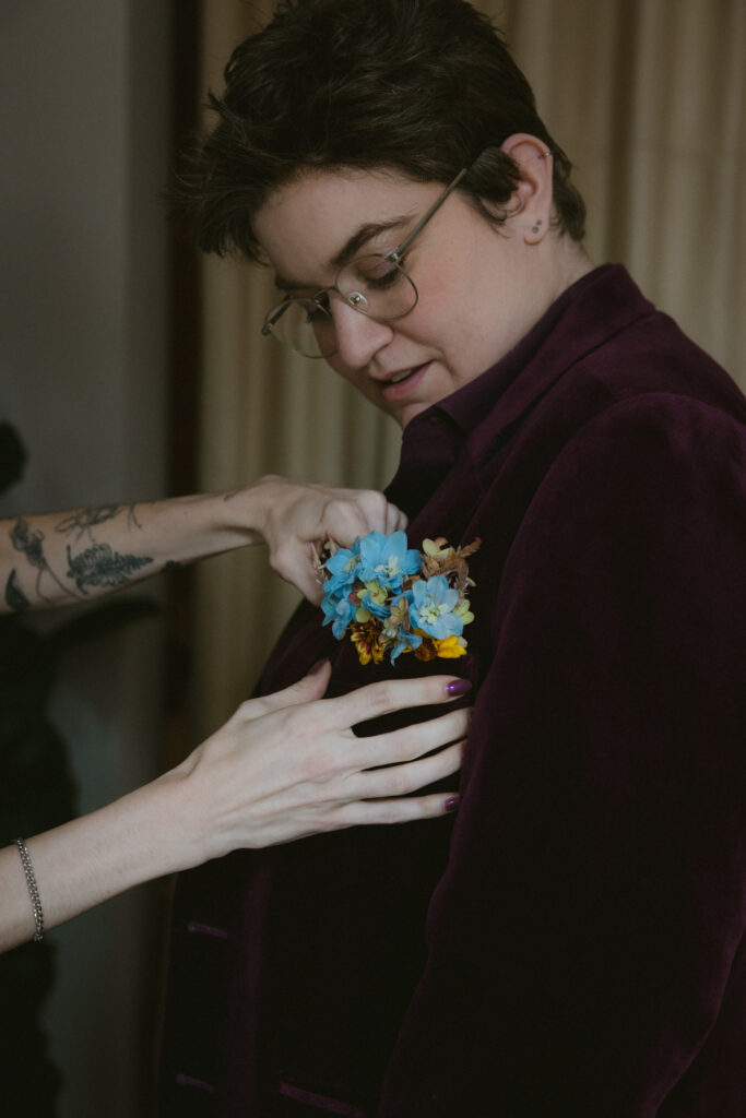 Bride putting boutonniere on suit