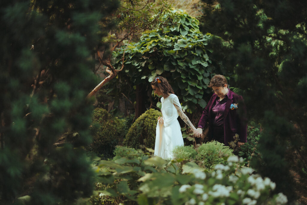 Brides walking through a garden holding hands