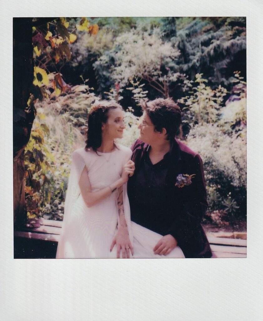 Polaroid of brides sitting on a bench, looking at each other