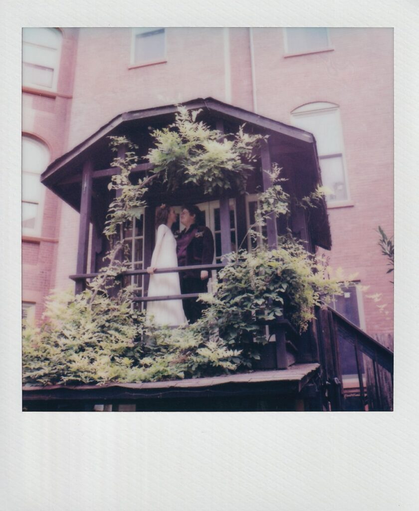 Polaroid of brides on a balcony, looking at each other