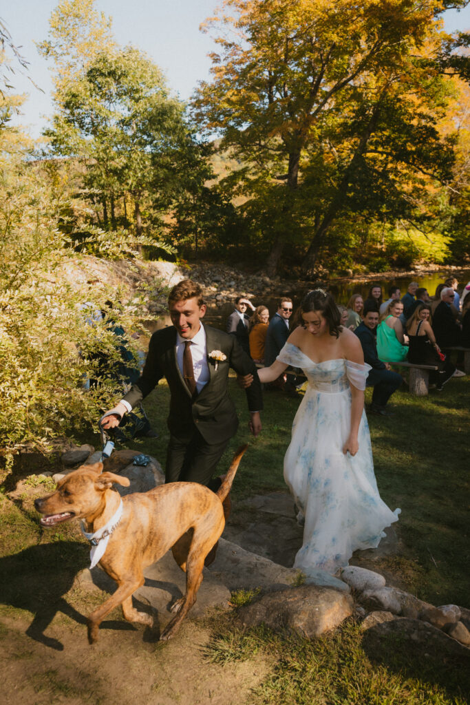 Bride and groom walking back down the aisle with their dog after getting married