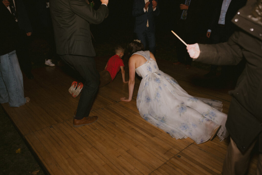 Bride and child doing the worm on the dance floor during the wedding reception