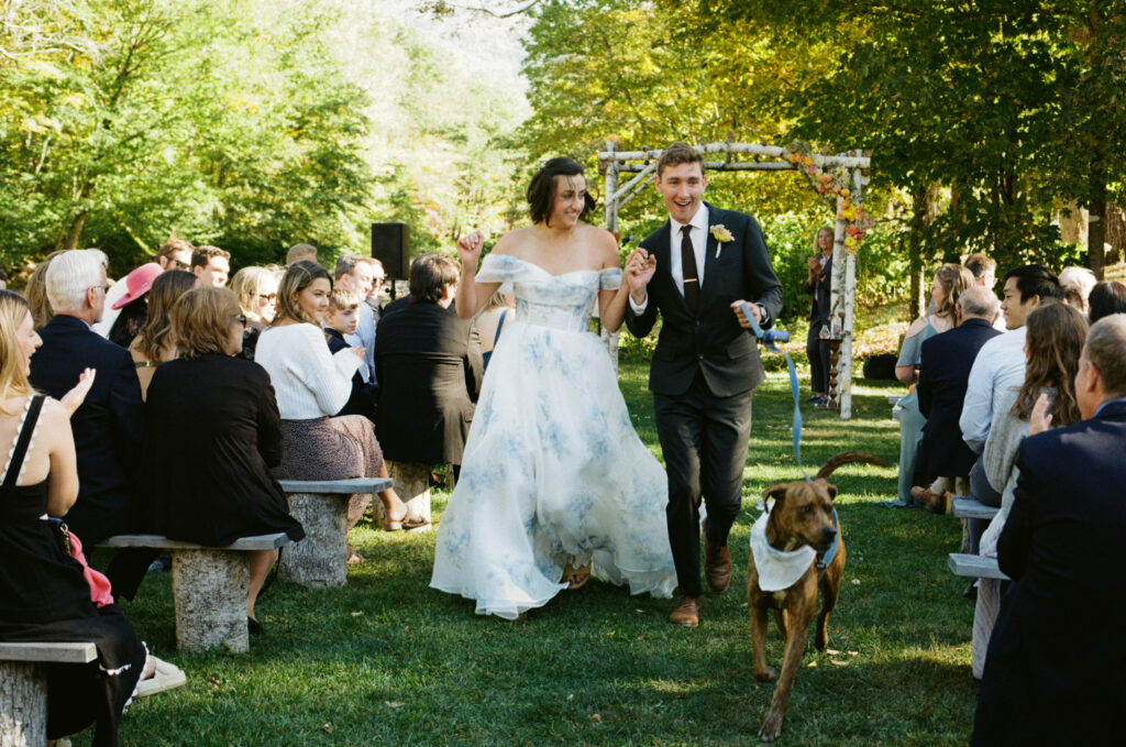 Bride and groom walking back down the aisle with their dog after getting married