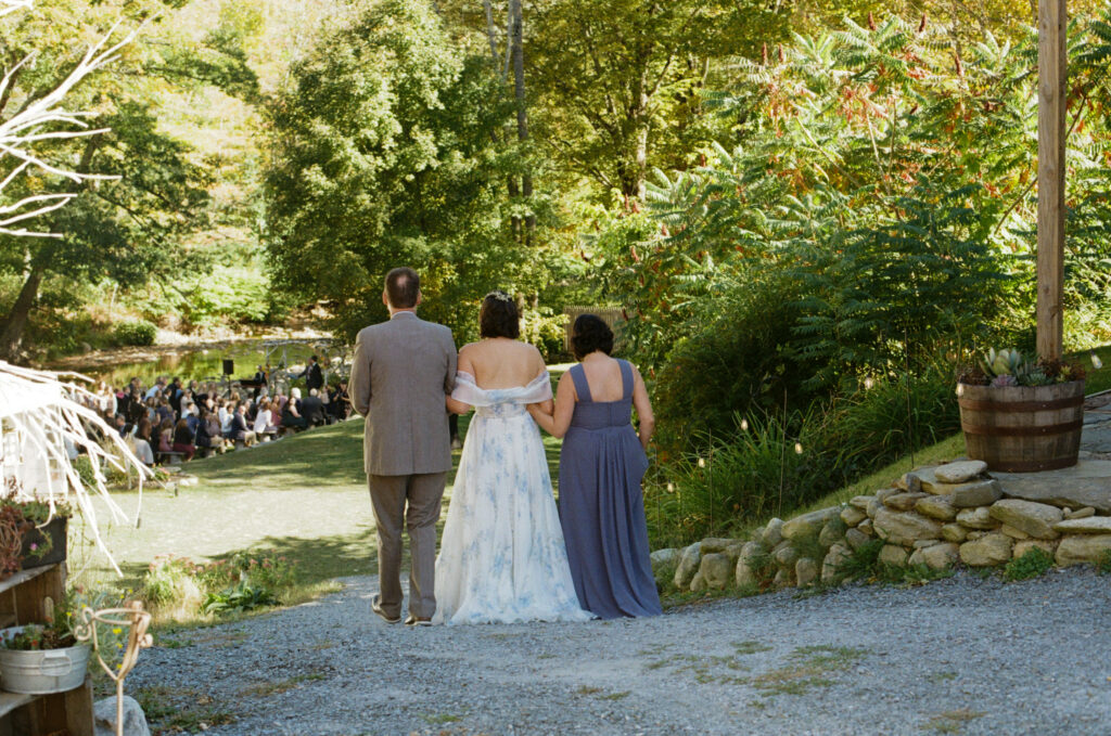Bride walking down the aisle with her parents, shot from behind