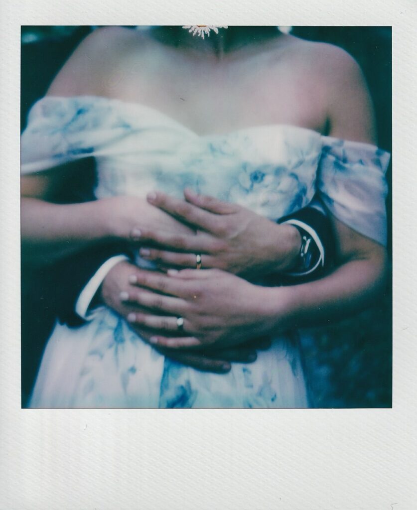 Polaroid of bride standing in front of groom while holding hands