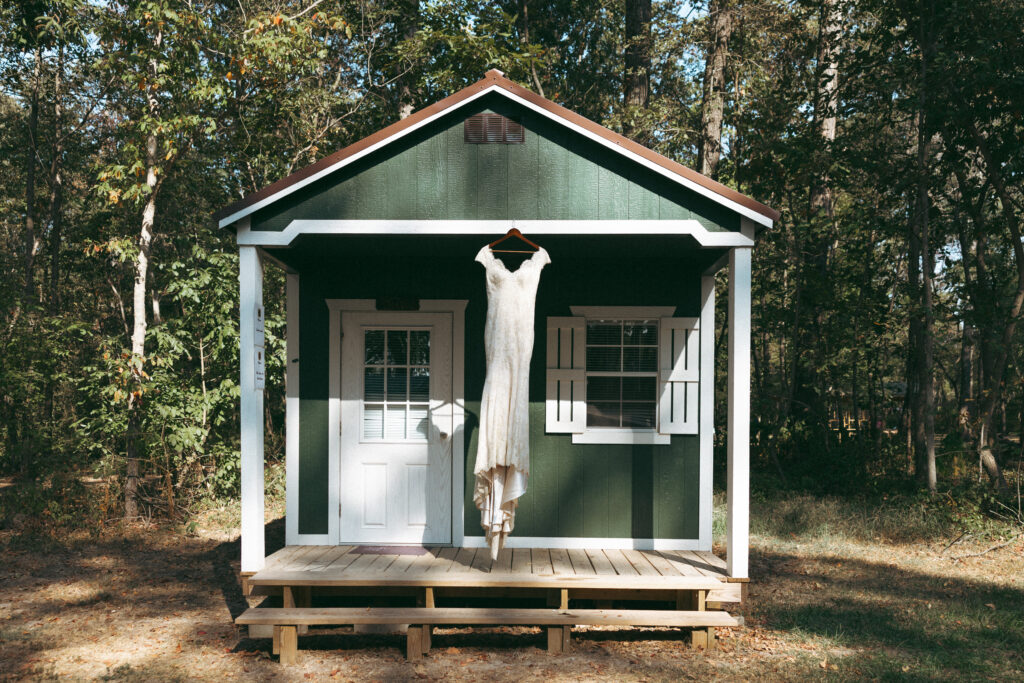 Wedding dress hanging in front of a cottage at a summer camp wedding venue