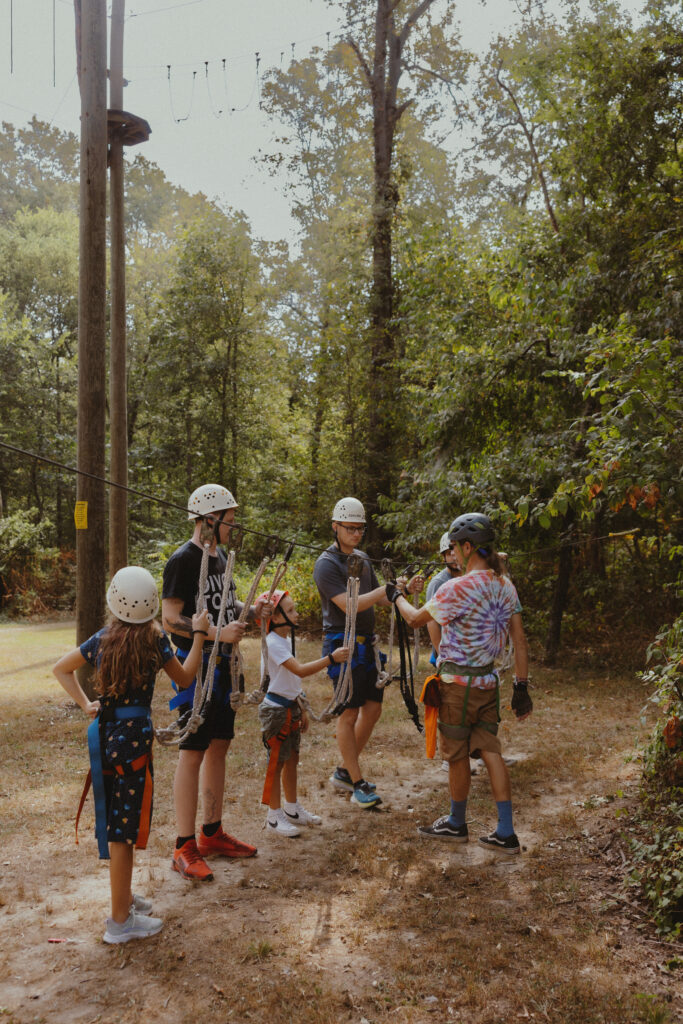 Groom and kids getting fitted for rock climbing and zip-lining 
