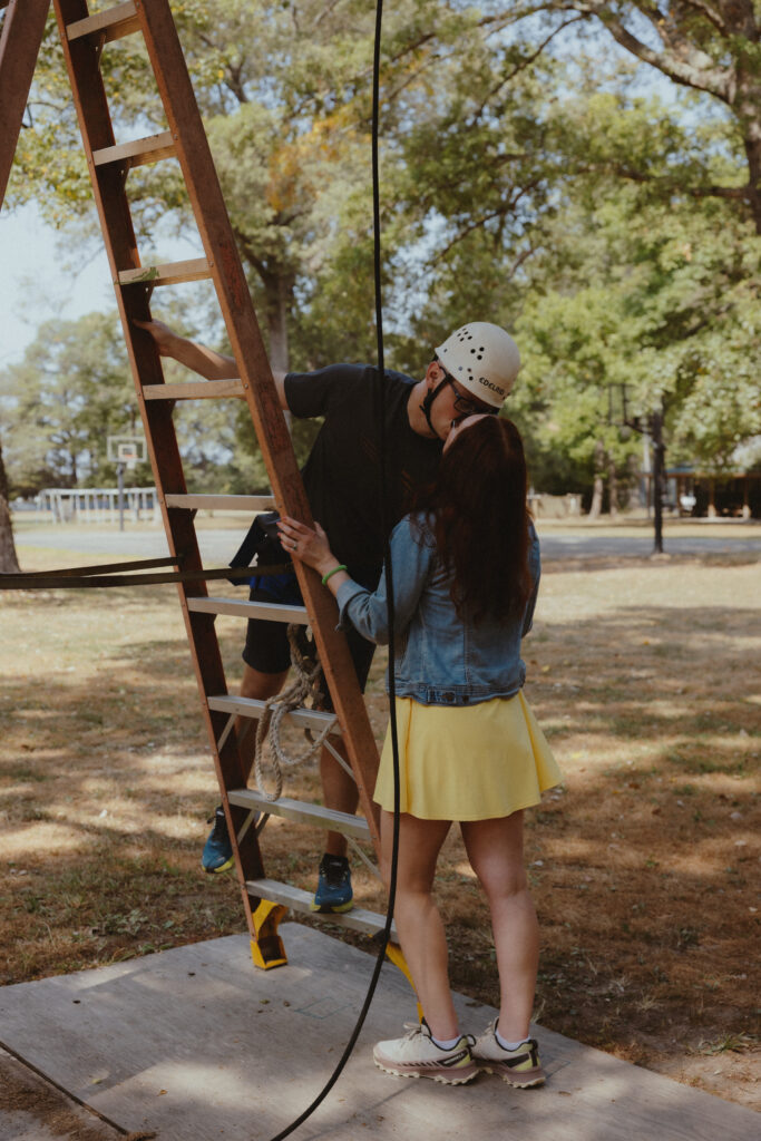 Groom and bride kissing after zip lining at a summer camp wedding venue