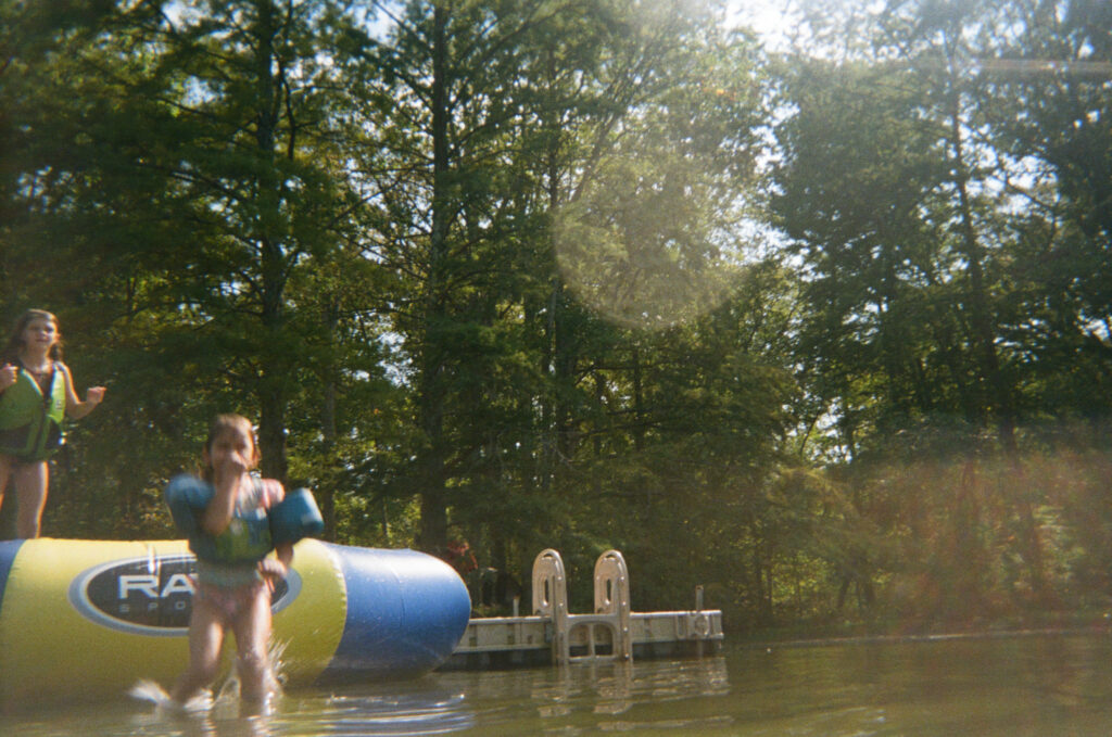 Children jumping into a lake at a summer camp wedding venue