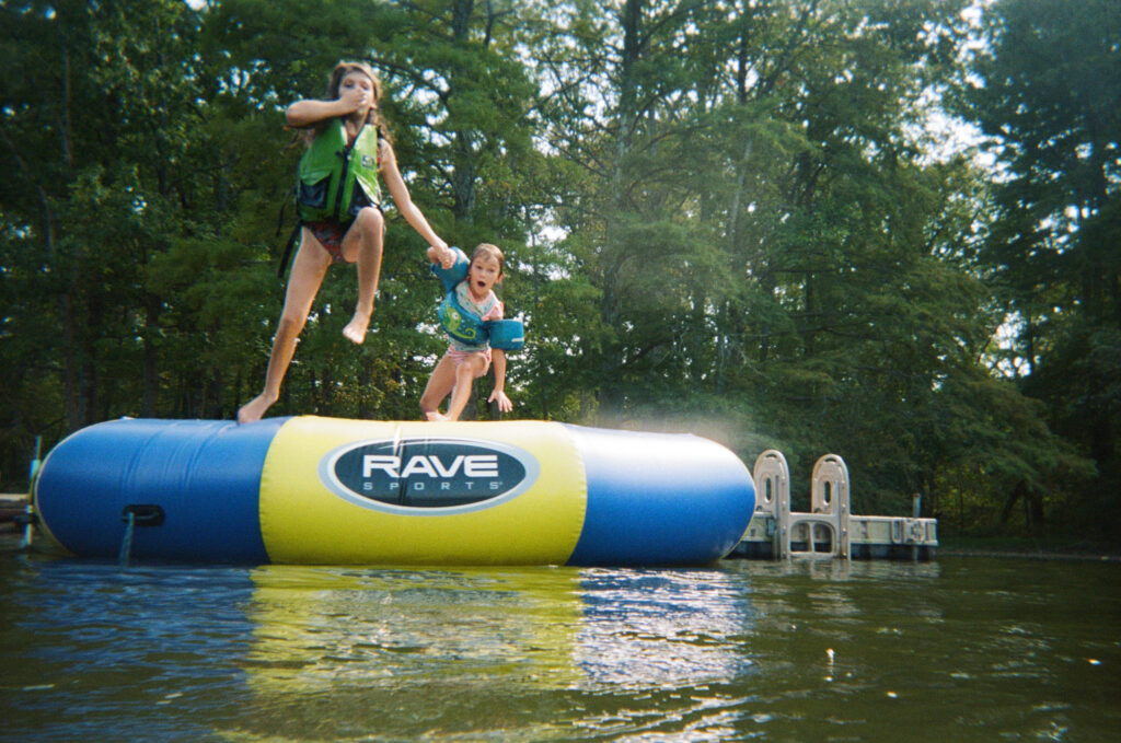 Children jumping into a lake at a summer camp wedding venue