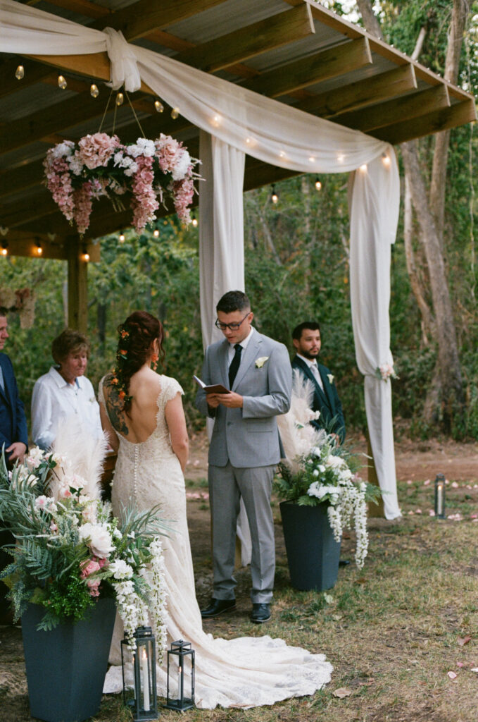 Groom reading his vows during the ceremony at a summer camp wedding