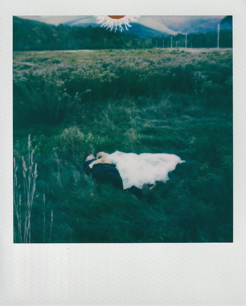 Polaroid of bride and groom laying in a meadow