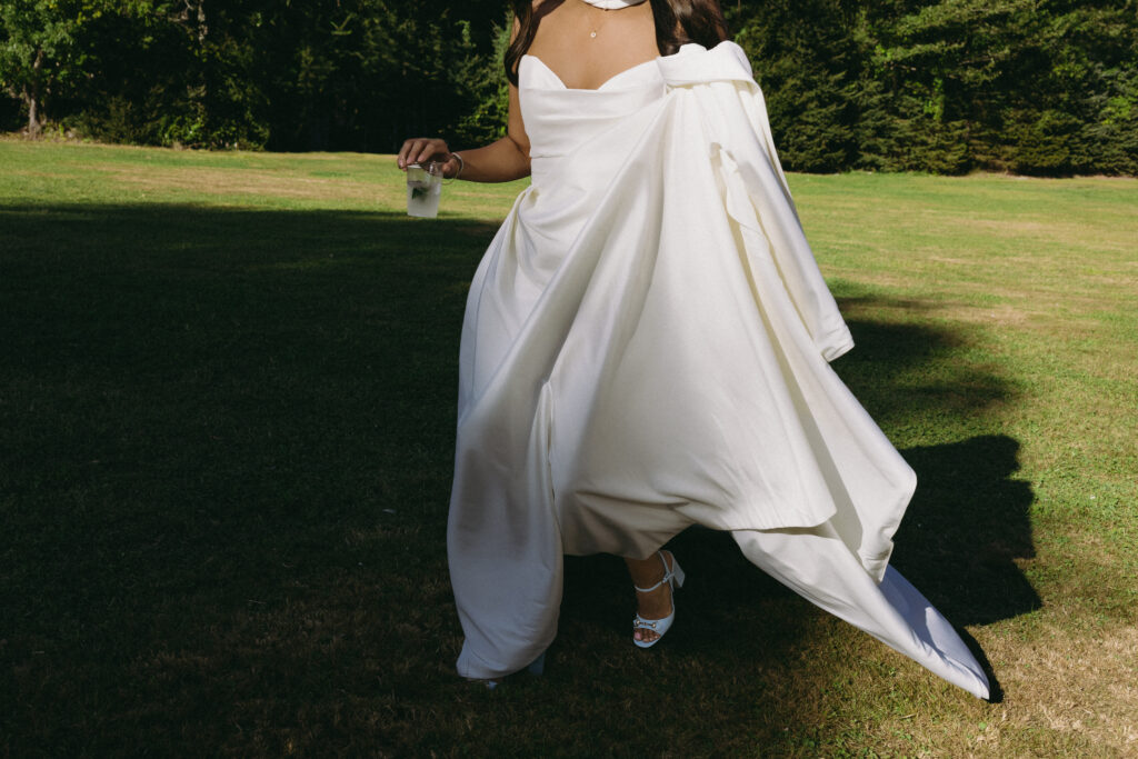 Bride walking across a lawn holding her dress up 