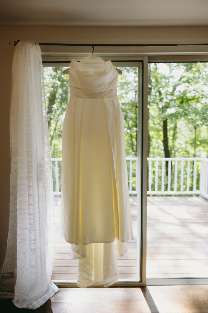 Wedding dress hanging in front of a window