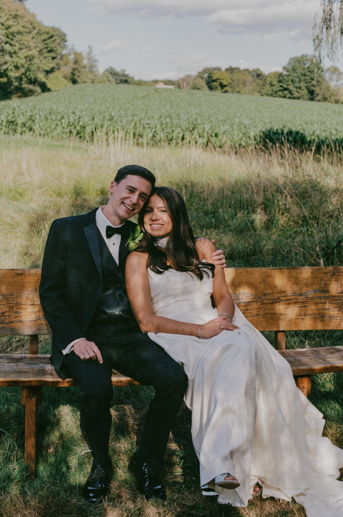 Bride and groom sitting on a bench at a New England farm wedding