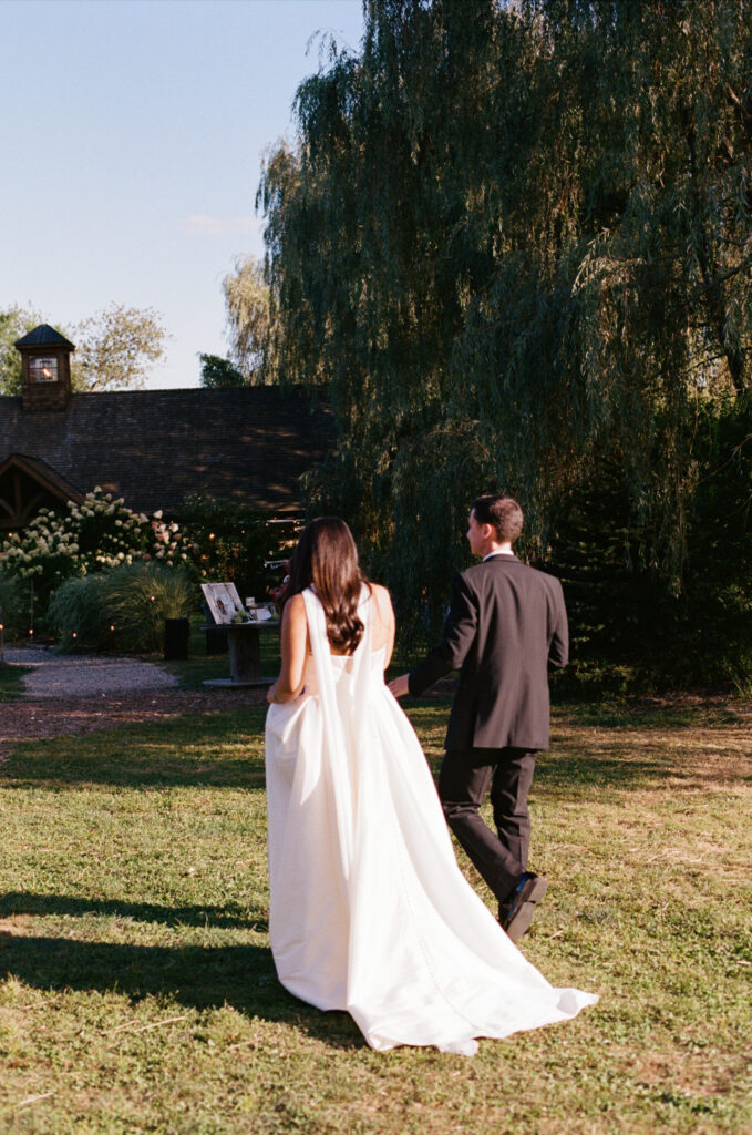 Bride and groom walking together from behind at a New England farm wedding