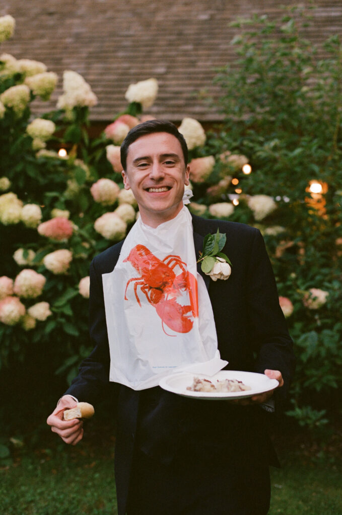 Groom wearing a lobster bib at a New England farm wedding