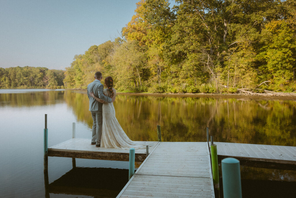 Bride and groom standing on a pier in front of a lake