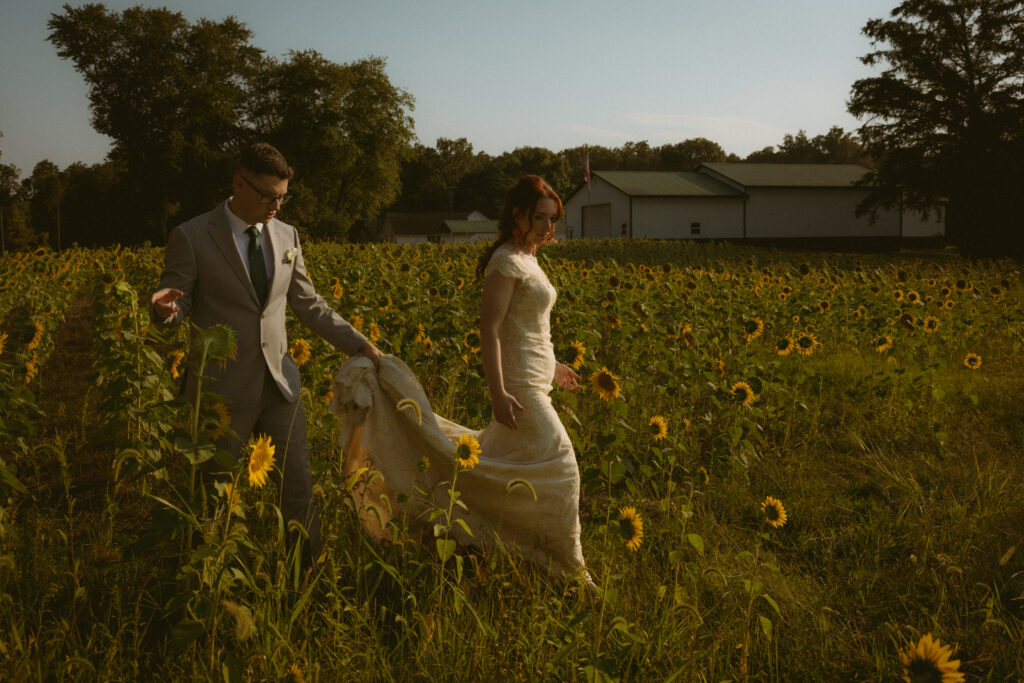 Bride and groom walking through a sunflower field