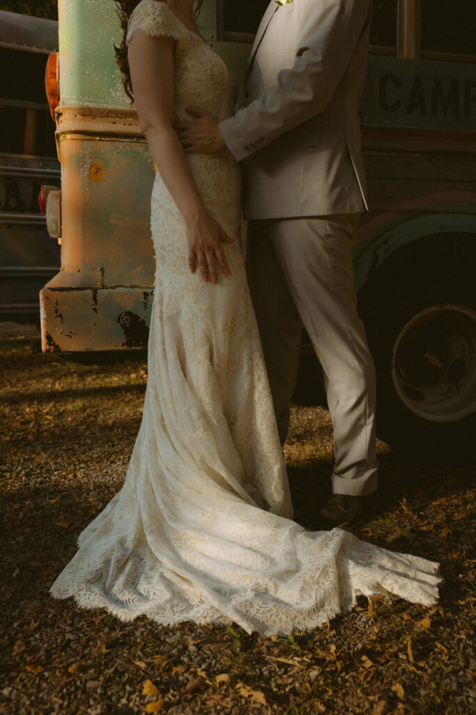 Bride and groom standing in front of a summer camp bus