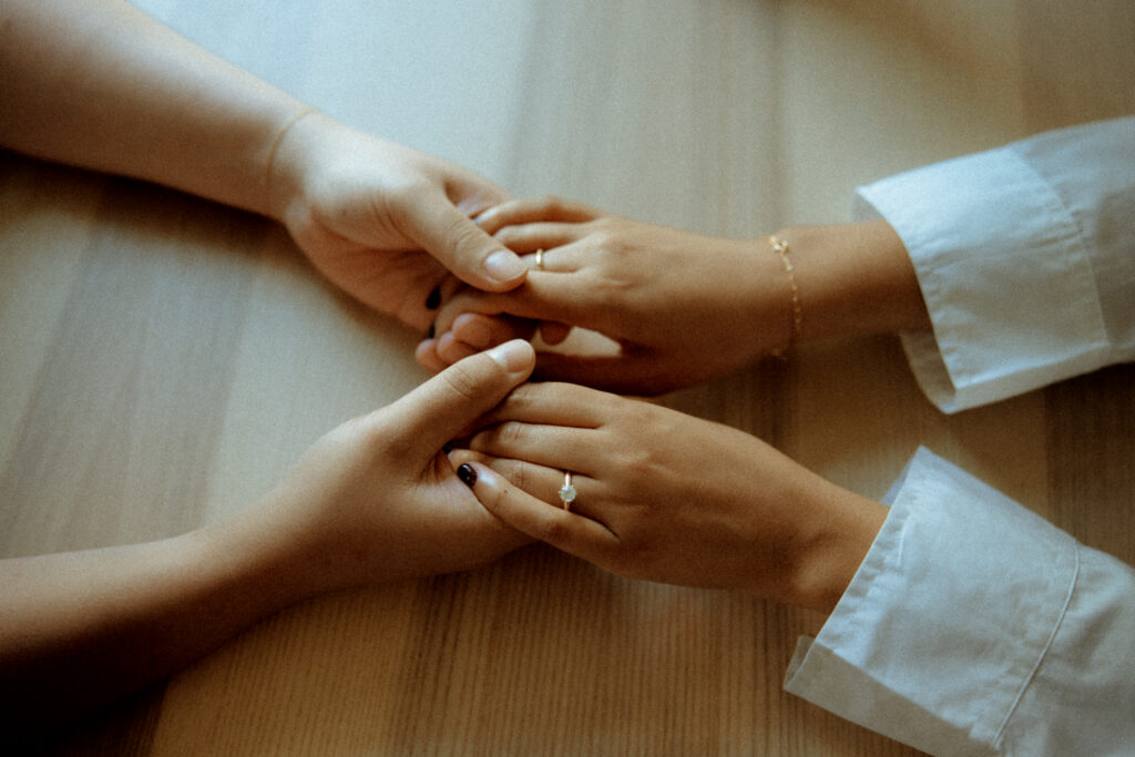 Close up of engaged couple holding hands across a table
