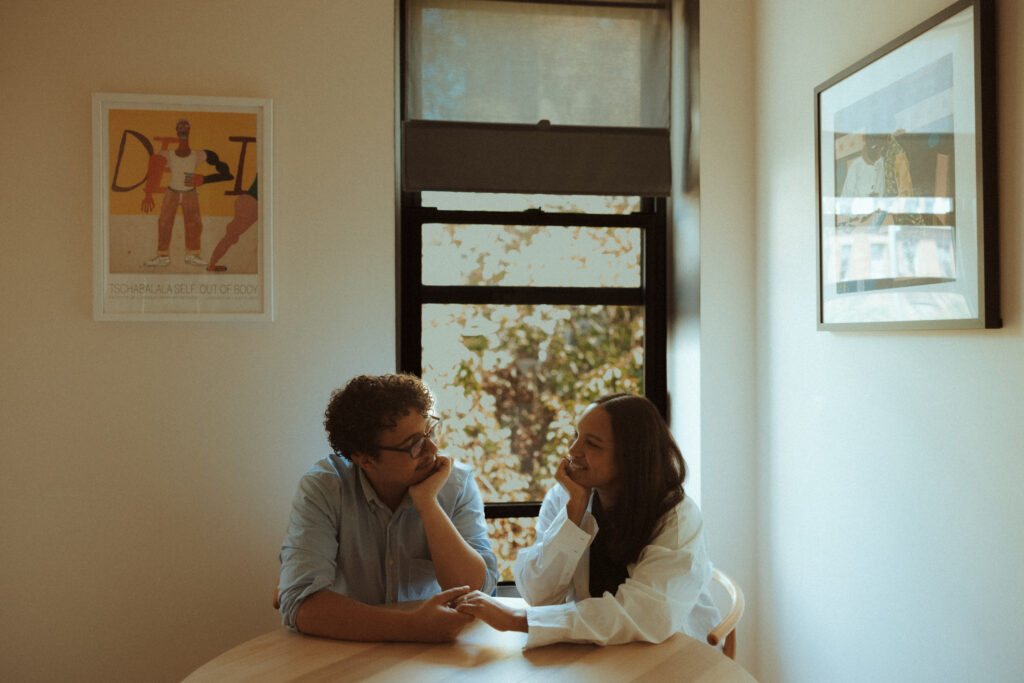 Engaged couple smiling and looking at each other at the kitchen table
