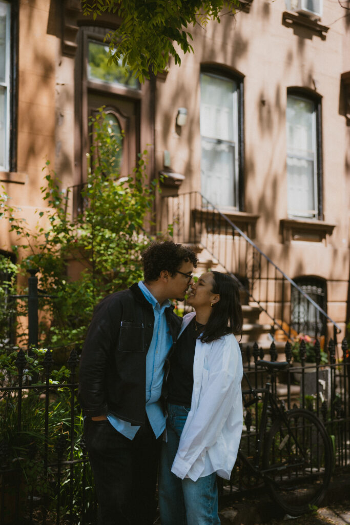 Engaged couple kissing in front of a Brownstone building in Brooklyn