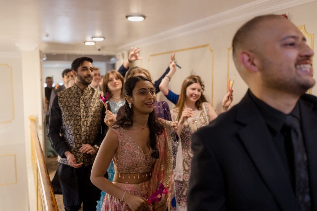 Family and friends cheering and leading the beginning of the ceremony at a Hindu Jewish wedding